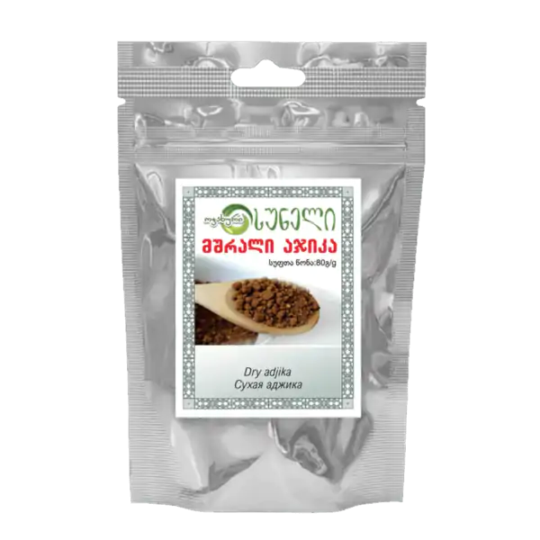 Balíček sušenej adjiky, tradičného gruzínskeho korenia, v striebornej fóliovej taške s nálepkou s gruzínskym písmom a obrázkom lyžice so suchou adjikou